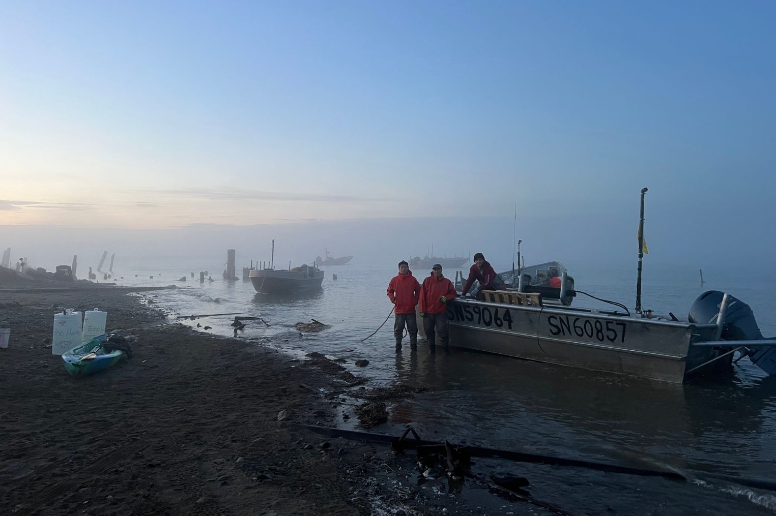 Commercial Fishermen standing next to set net skiff in Koggiung, Alaska located in Bristol Bay.