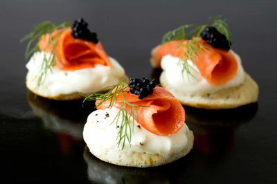 Nova Style Wild Alaskan Smoked Salmon sliced and folded on top of cream cheese and crackers.