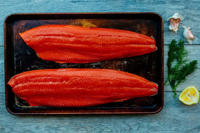 Wild Caught Alaskan Sockeye Salmon filets unprepared on a baking sheet with a deep red color since they are raw.