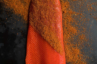 Wild caught Alaskan salmon filet with seasoning sprinkled on top of the filet, raw and ready to cook.
